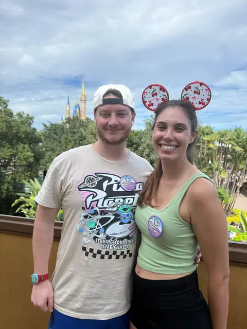 Katie in cherry Minnie ears and David in a backwards cap with the castle at Magic Kingdom behind them