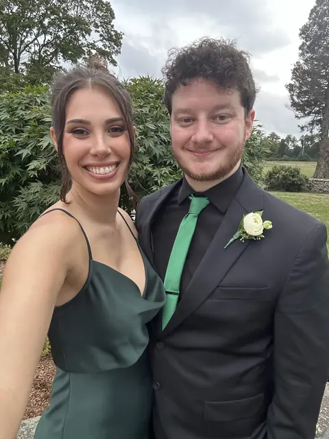 Katie in an emerald dress and David in a black suit with a green tie and white boutonniere